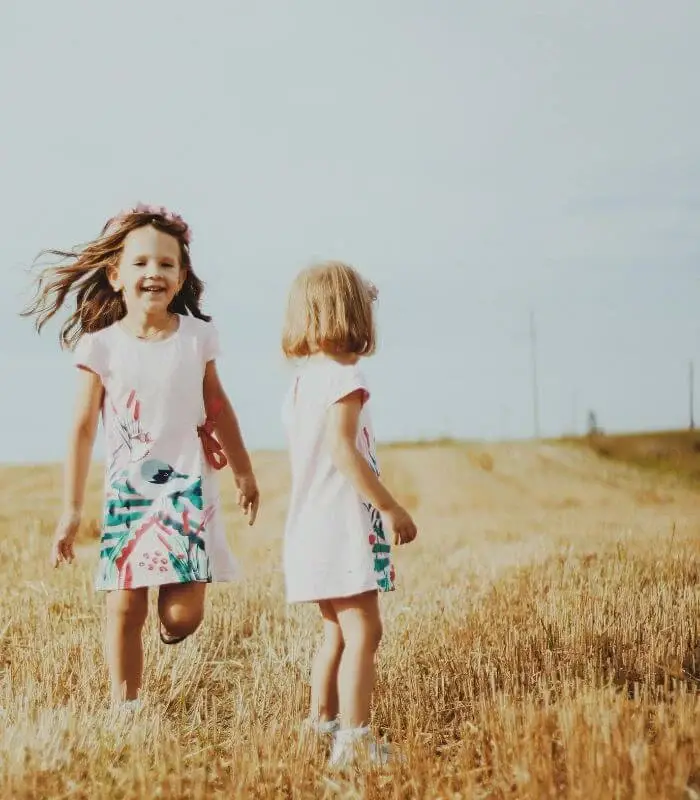 Deux enfants qui courent dans un champ de blé, illustrant l’exploration de l’enfance en psychothérapie