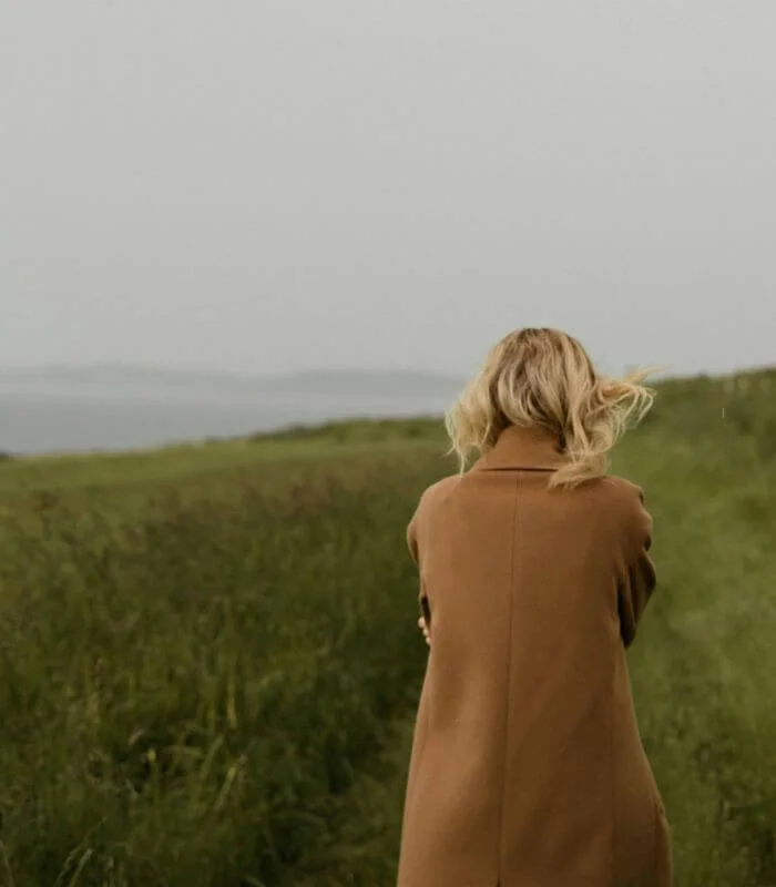 Femme en pleine introspection qui marche dans l'herbe, illustration d’une démarche de réflexion personnelle