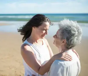 Femme adulte avec sa mère à la plage, illustrant une transition de vie
