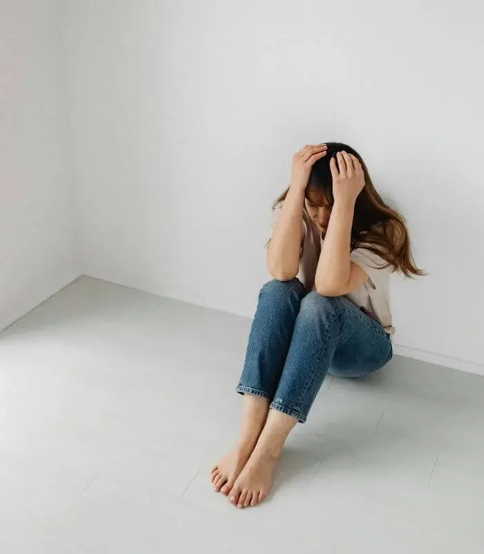 Femme assise dans un coin de la pièce, illustration d’une souffrance psychologique nécessitant un accompagnement adapté