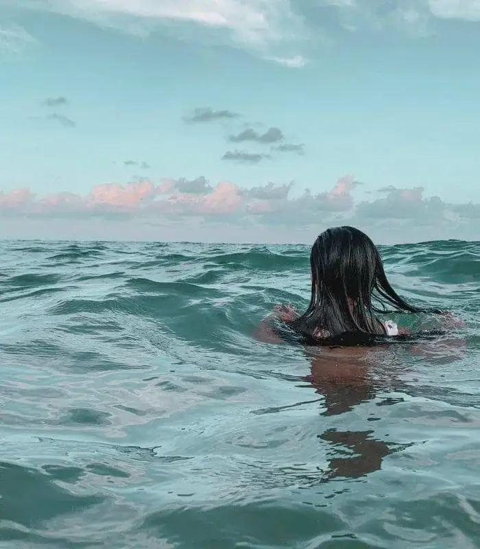 Femme qui nage dans la mer et réfléchit à ses croyances limitantes